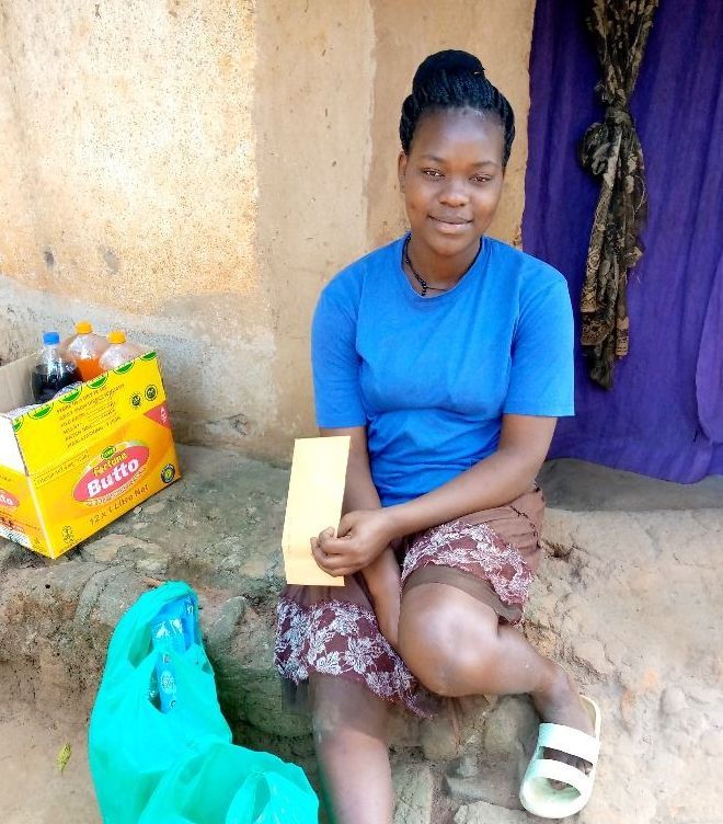 A woman in a blue shirt sits in front of a box that says dutta