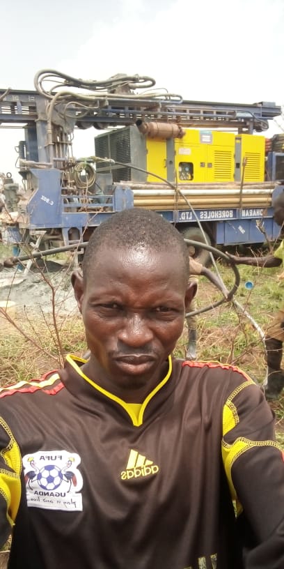 A man wearing an adidas shirt is standing in front of a machine.