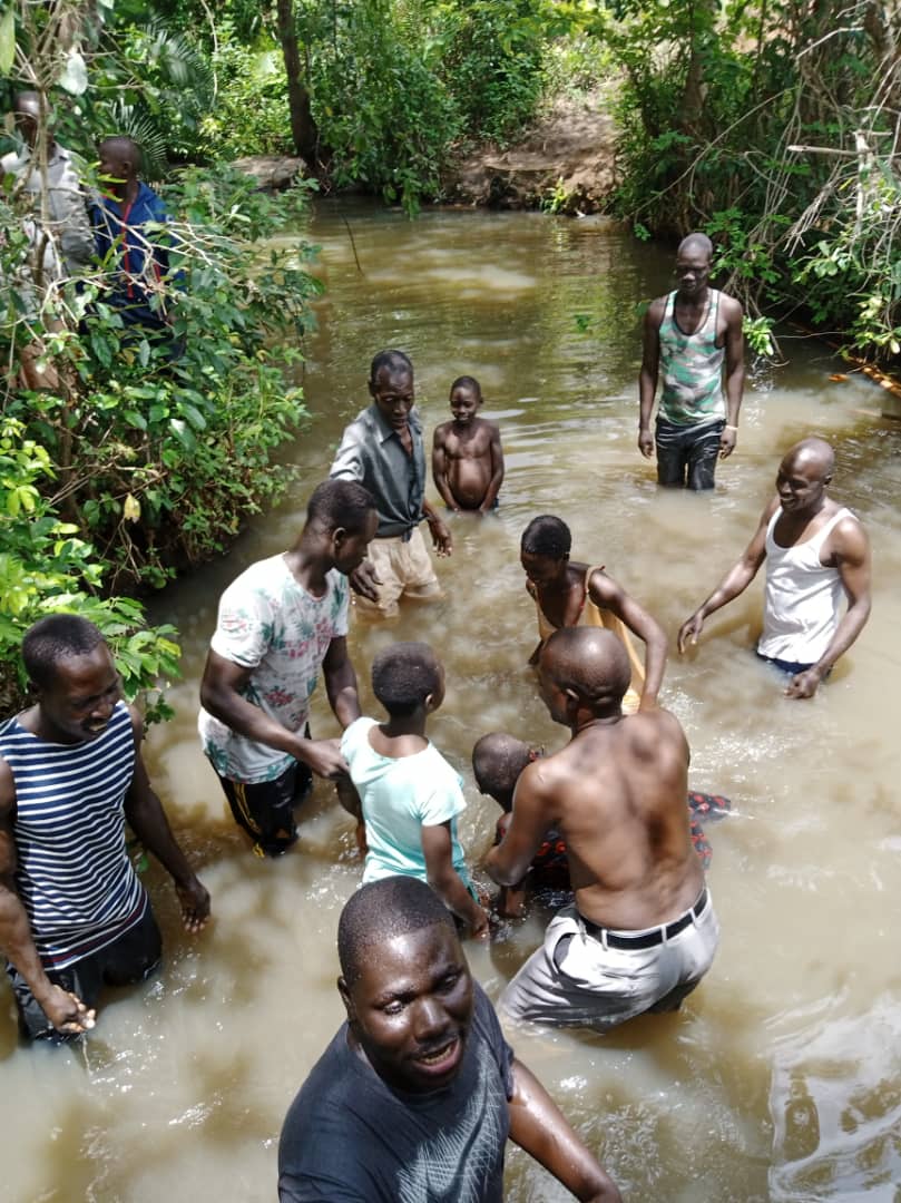A group of people are kneeling in a river.