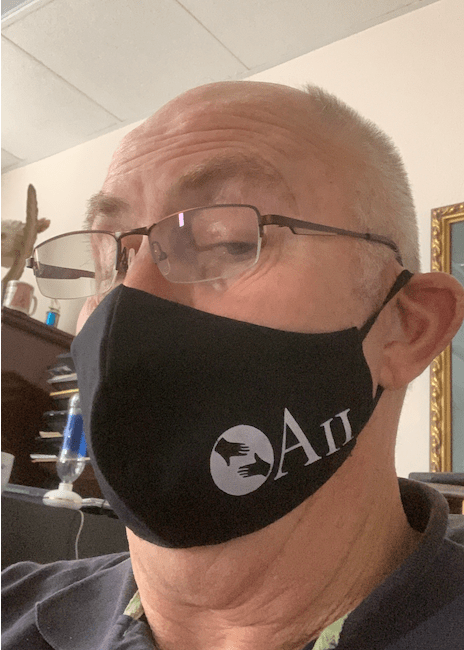 A man wearing glasses and a black face mask that says au