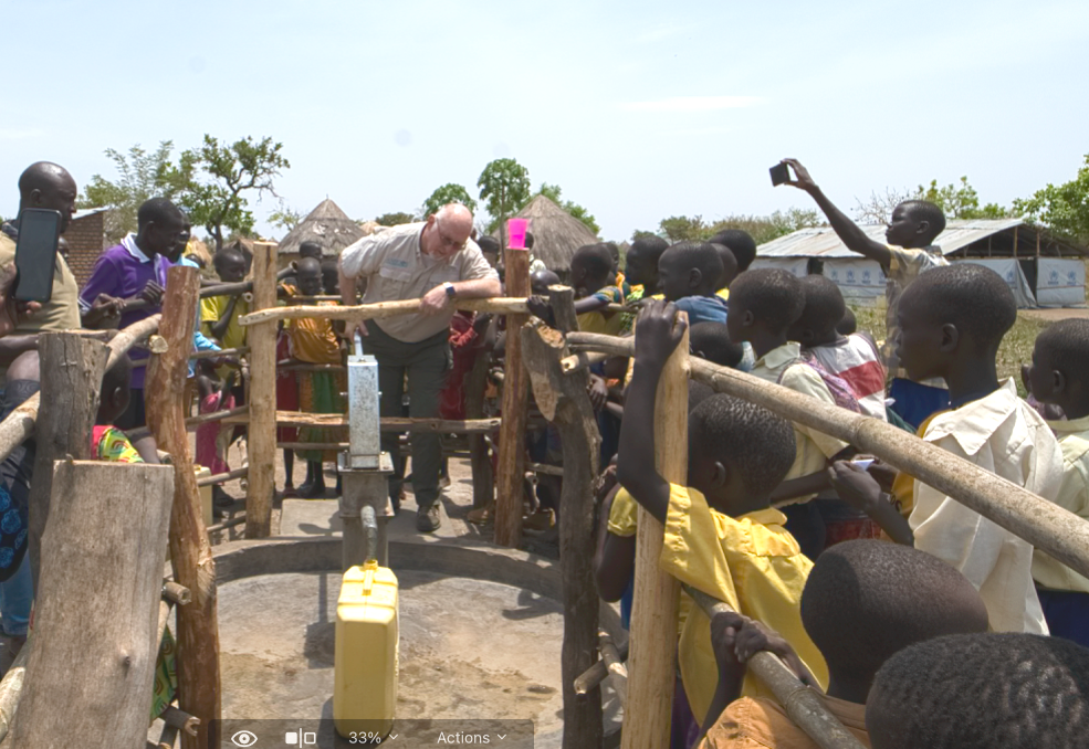 A group of people are gathered around a water pump