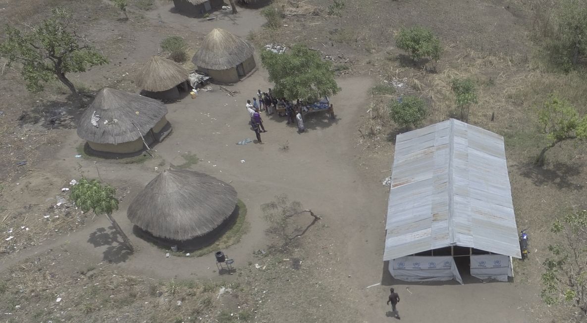 An aerial view of a village with huts and a tent.