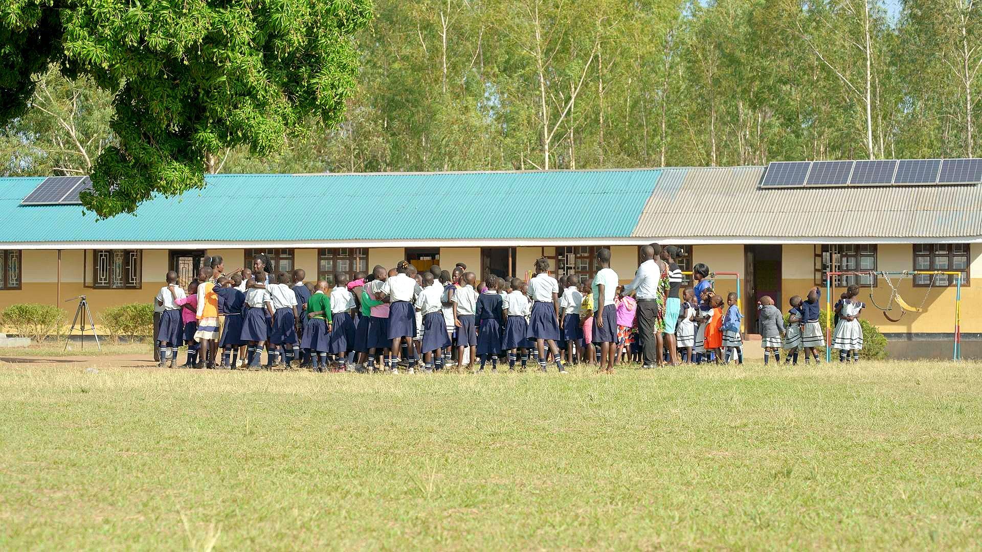 A group of children are standing in front of a school building