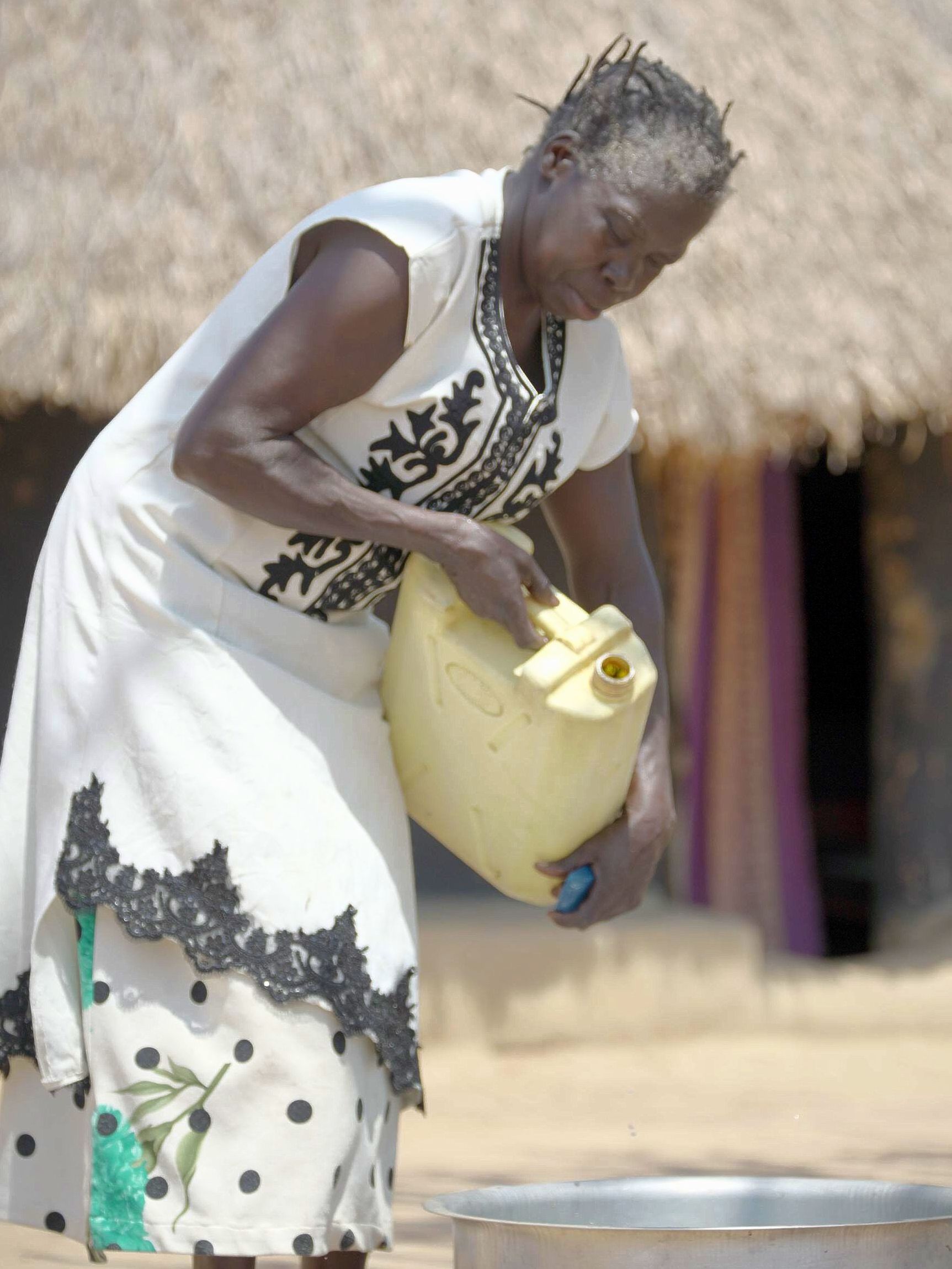 A woman in a white dress is pouring water into a bowl