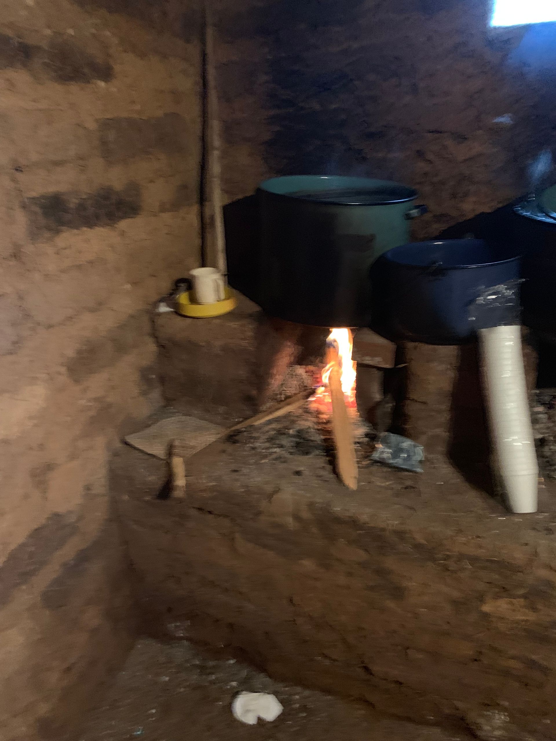 A pot is cooking on a fire in a room.