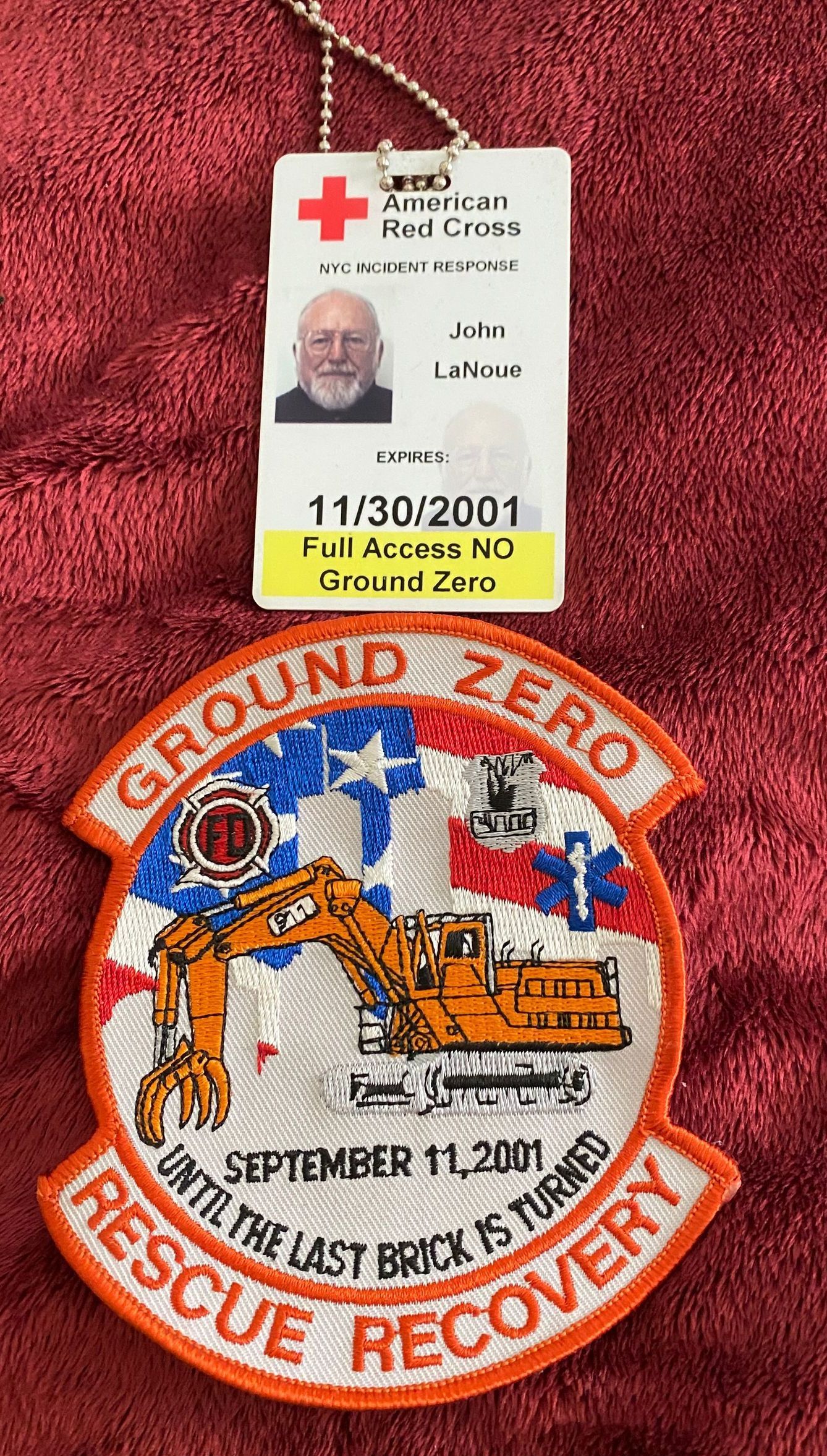 A man is wearing a red cross badge and a patch.