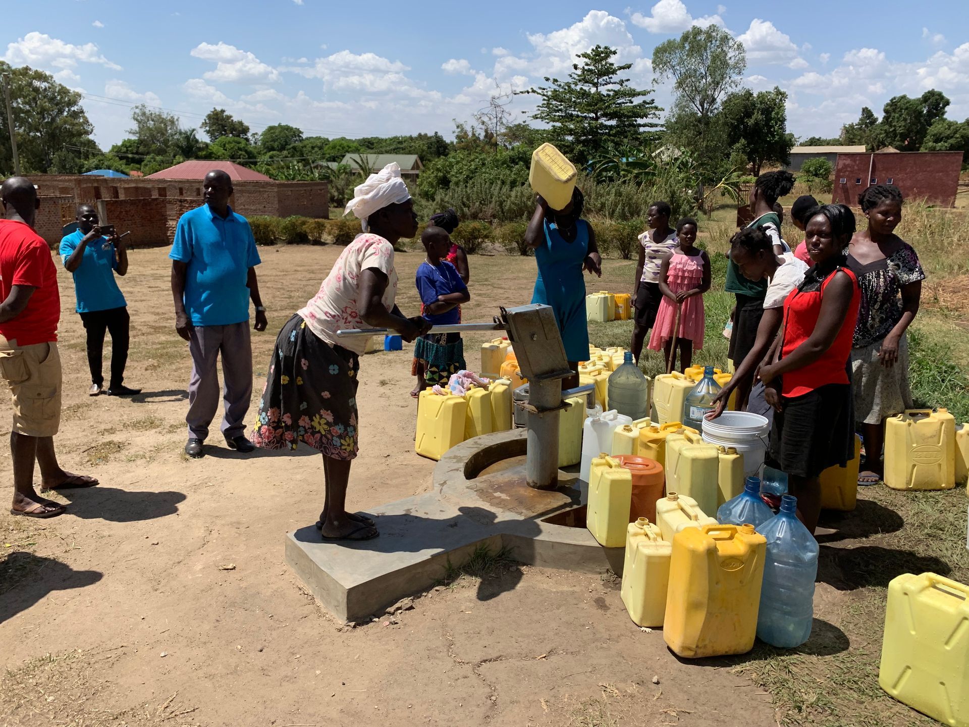 A group of people are gathered around a water pump.