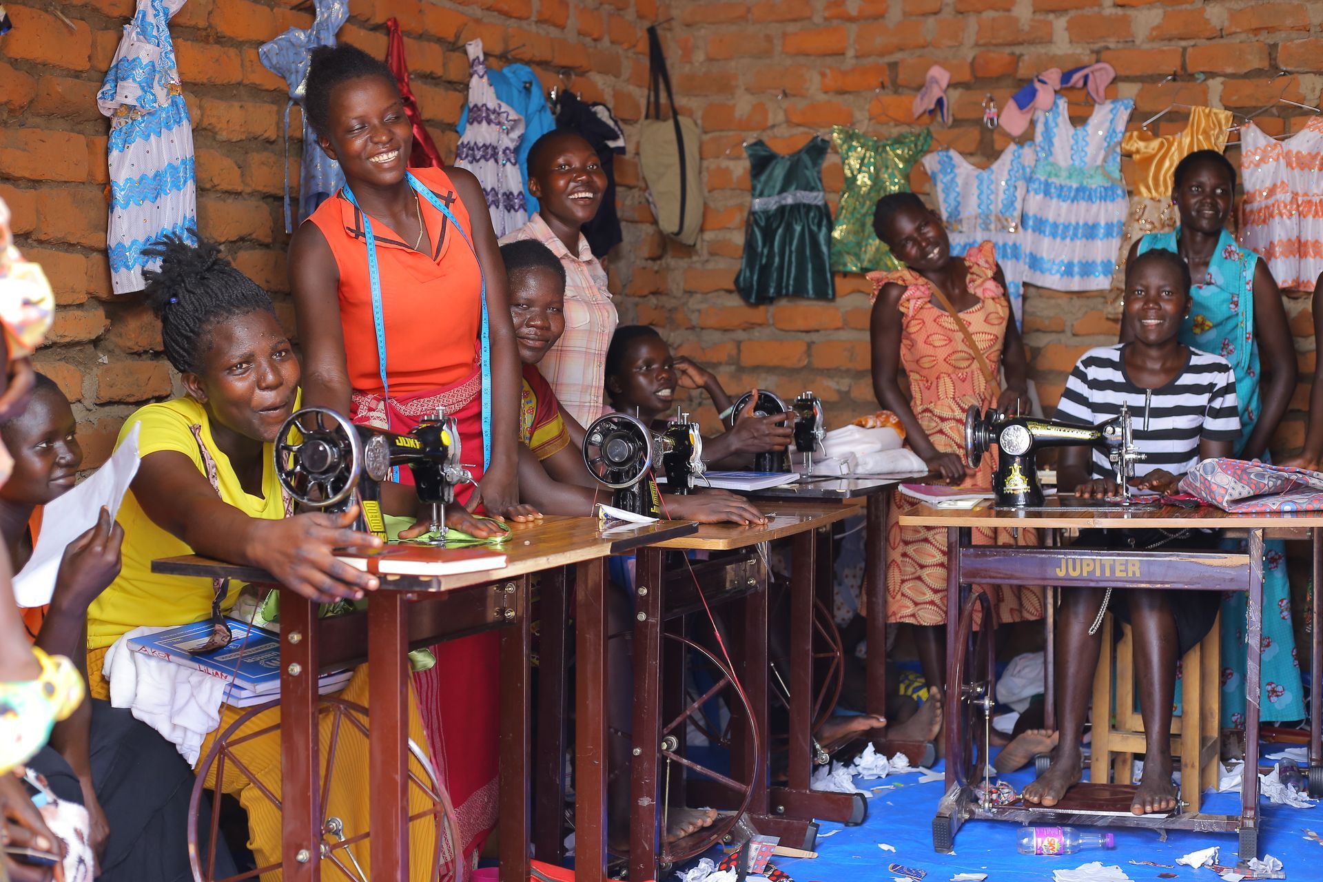 A group of people are sitting around sewing machines in a room.