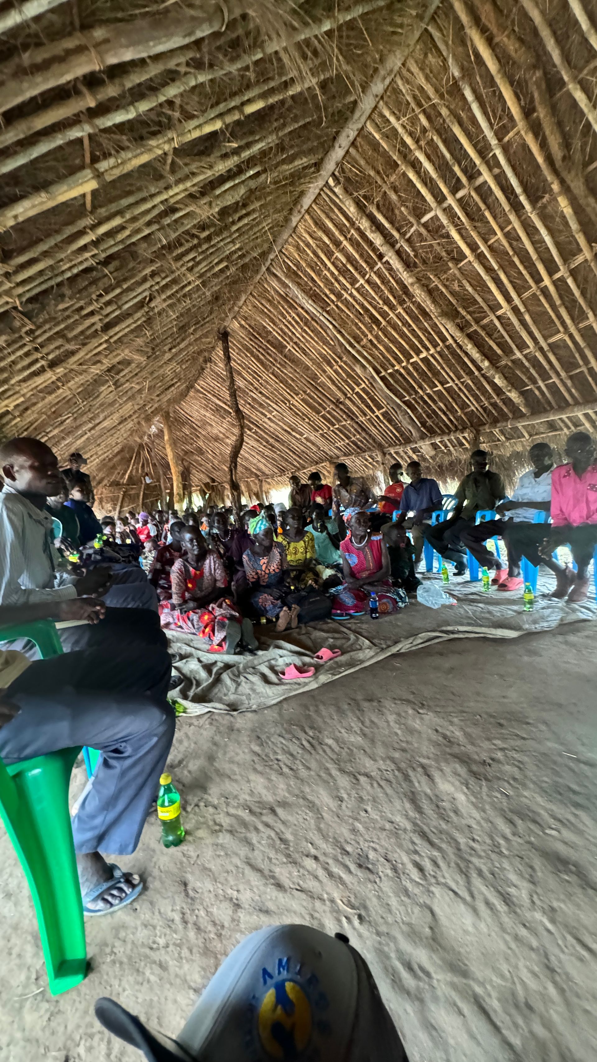 A group of people are sitting under a thatched roof.