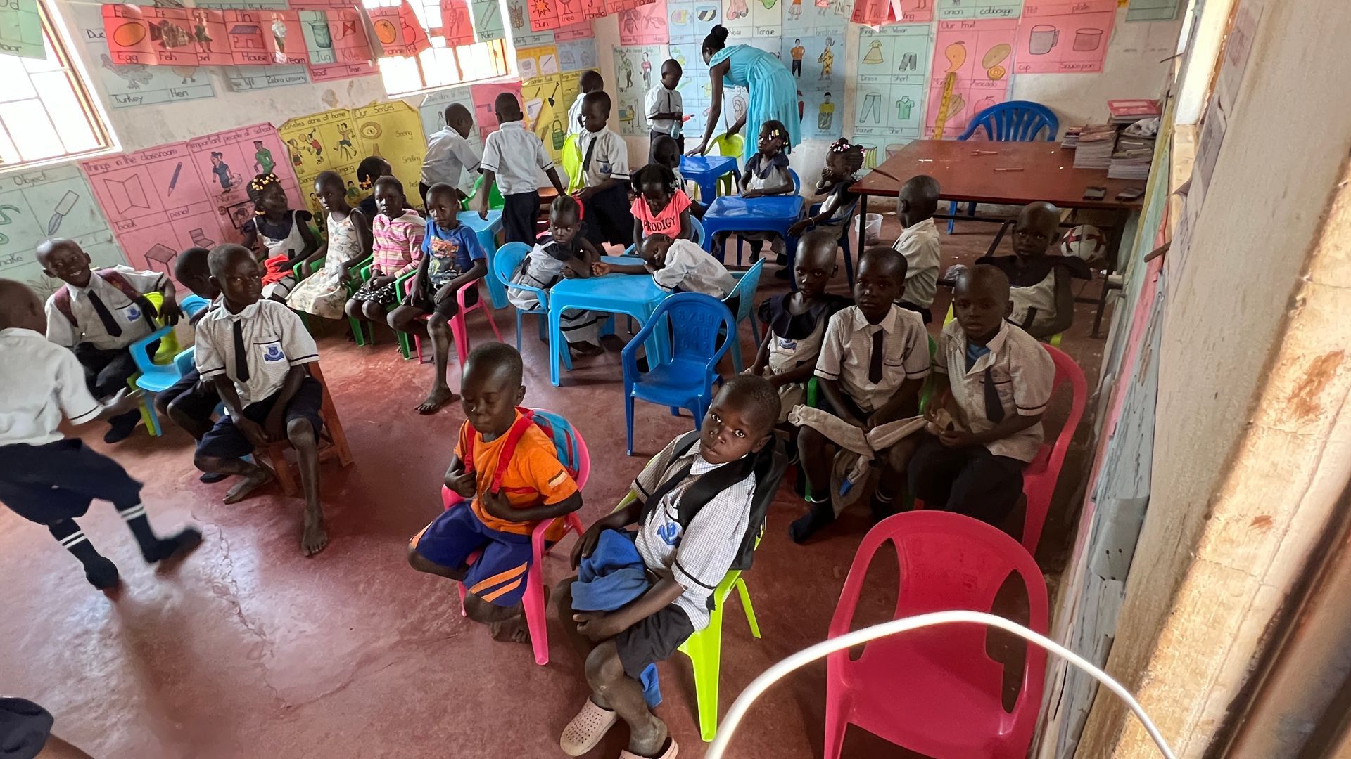 A group of children are sitting at tables in a classroom.