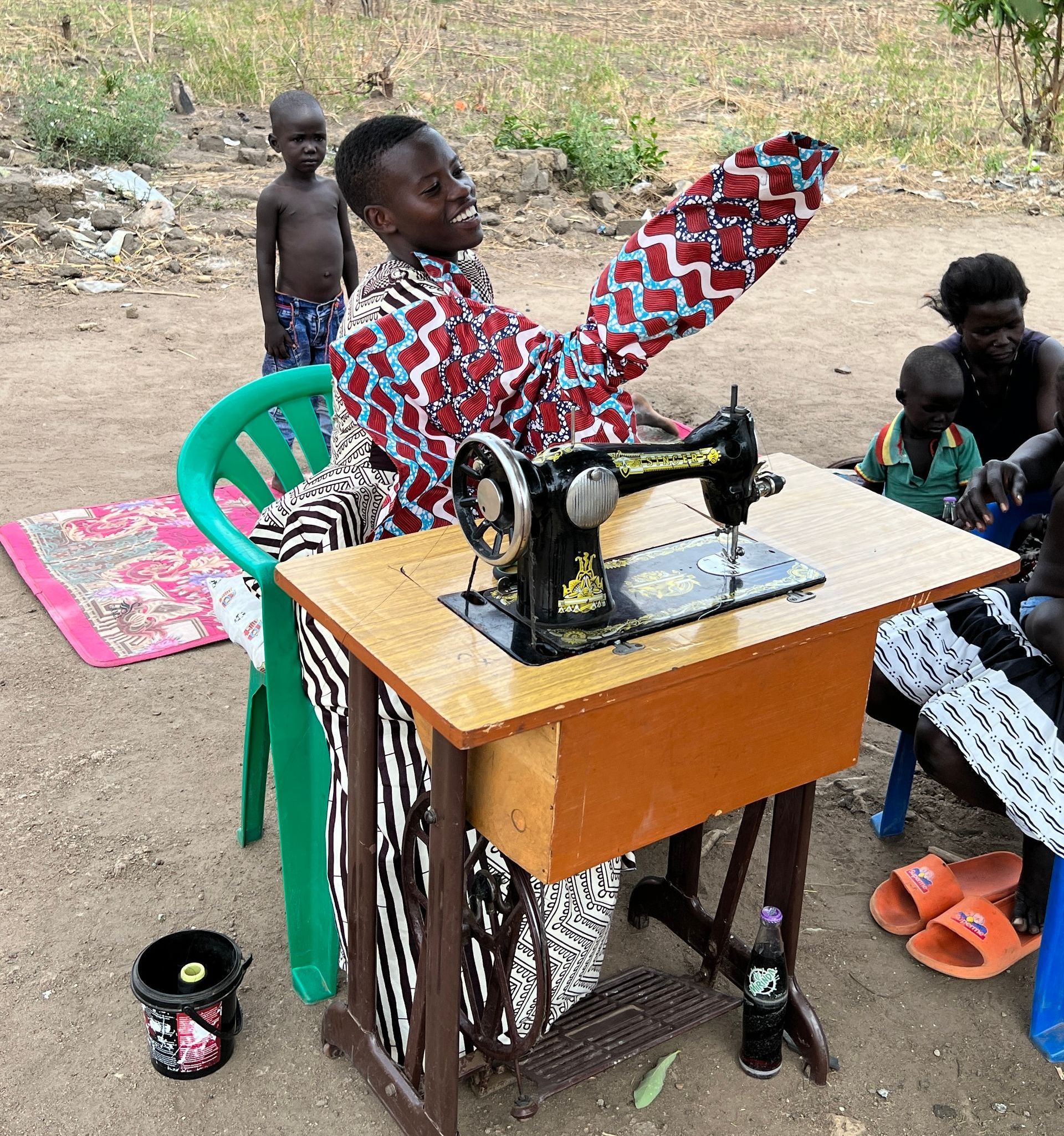 A man is sitting at a table using a sewing machine.