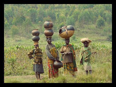 A group of women carrying pots on their heads in a field.