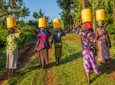 A group of women are carrying buckets of water on their heads.