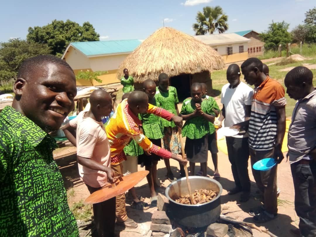A group of people are standing around a pot of food