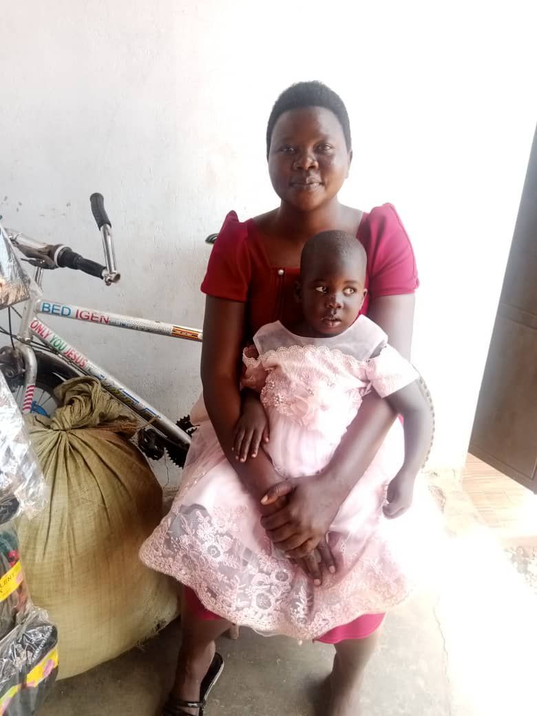 Woman in red dress holding a child in a pink dress, seated. They are smiling.