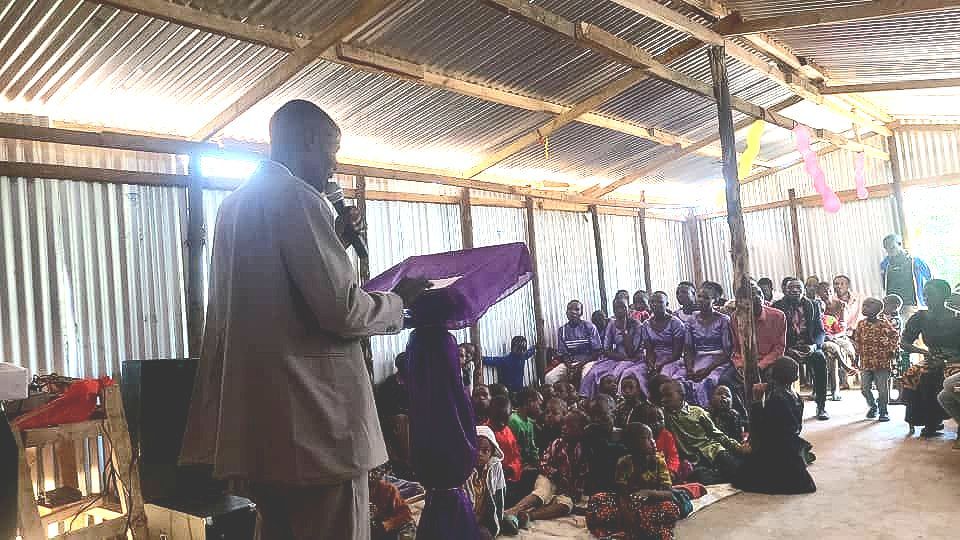 A man is standing in front of a crowd of people holding a microphone.