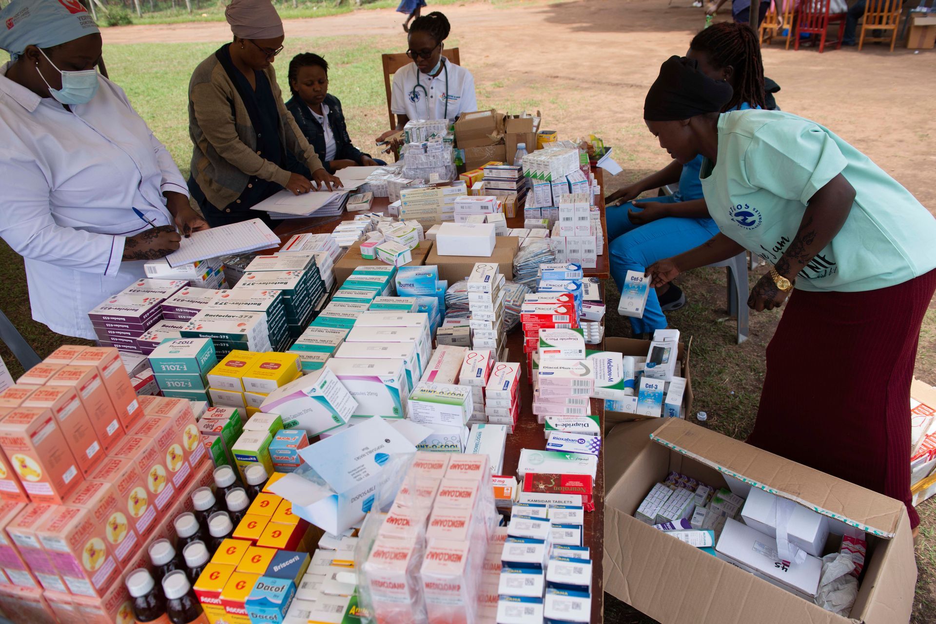 Medical professionals at a table sorting medications, likely at a health clinic or aid event.