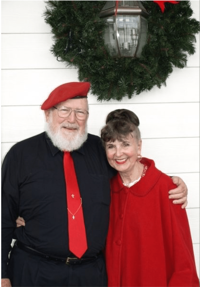 A man and woman are posing for a picture in front of a wreath.