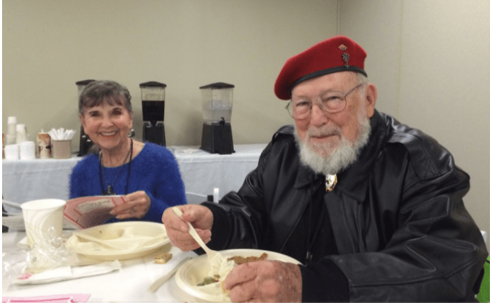 A man and a woman are sitting at a table eating food