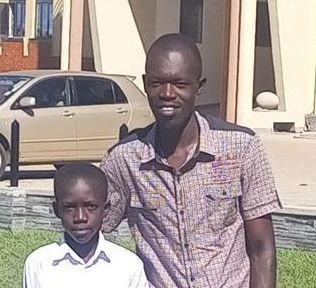 A man and a boy are posing for a picture in front of a car.