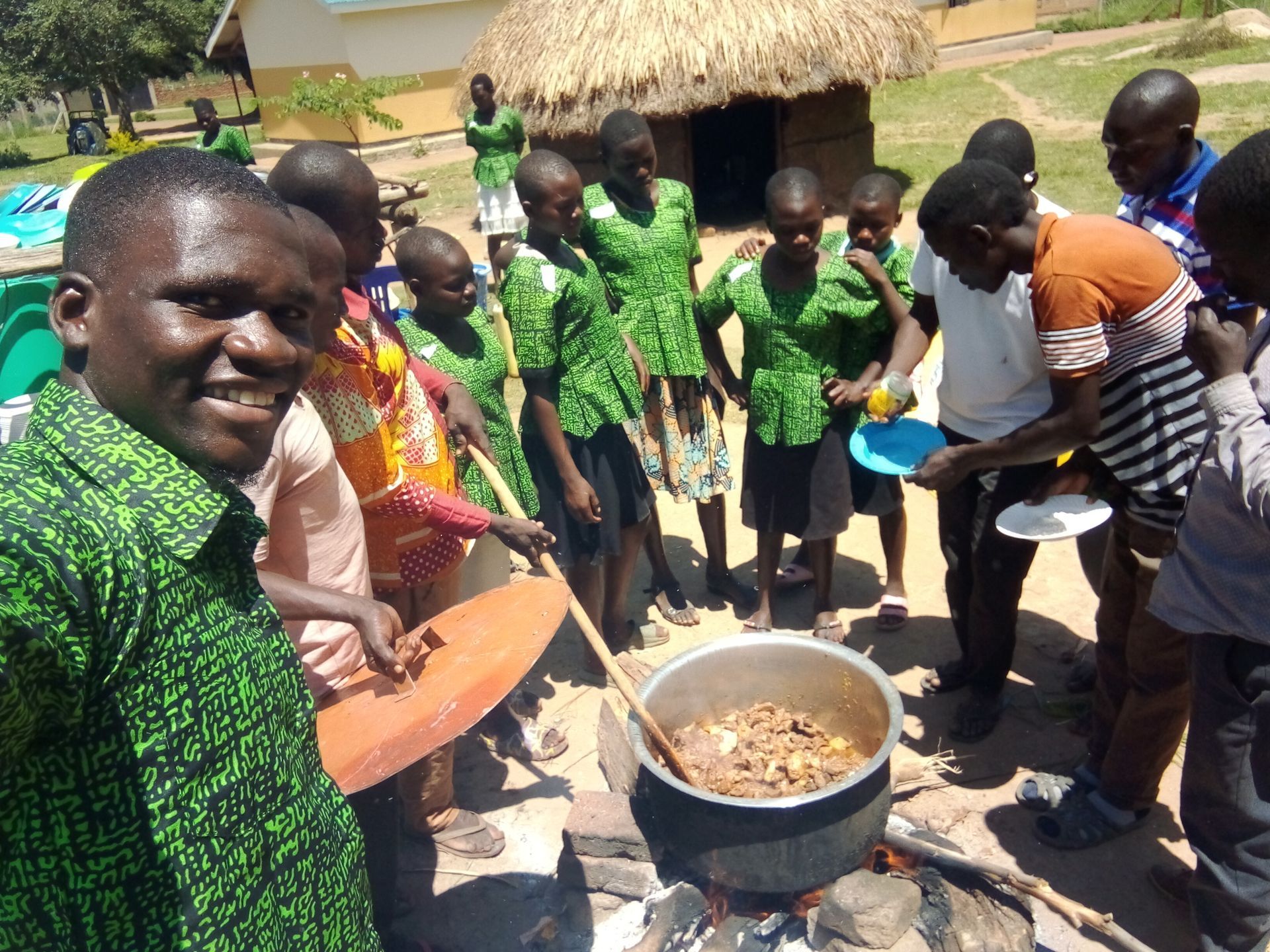 A group of people are standing around a pot of food