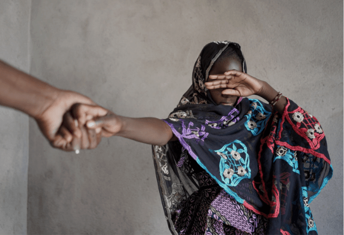 A woman covering her face with her hands while holding another person 's hand