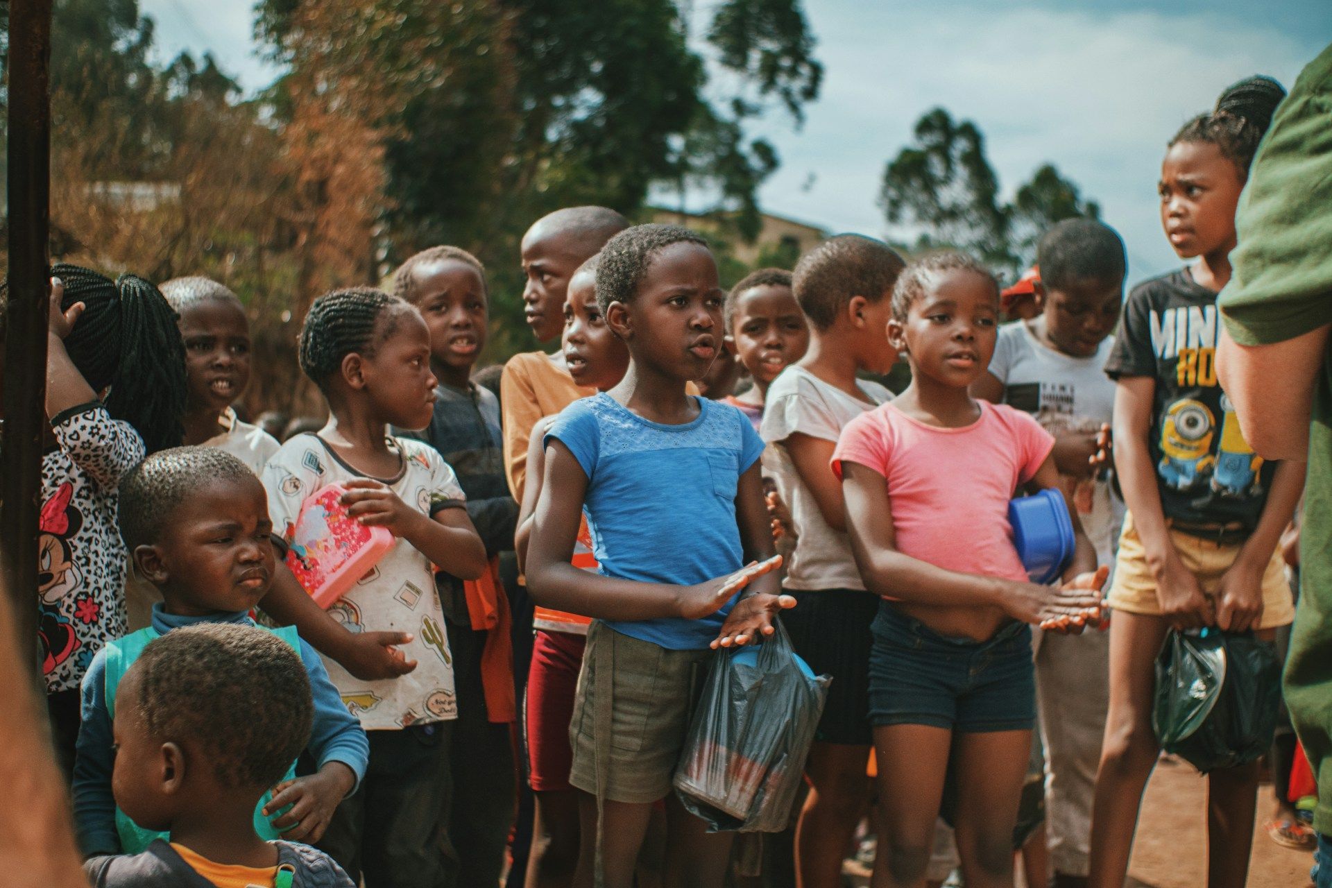 A group of children are standing in a line outside.