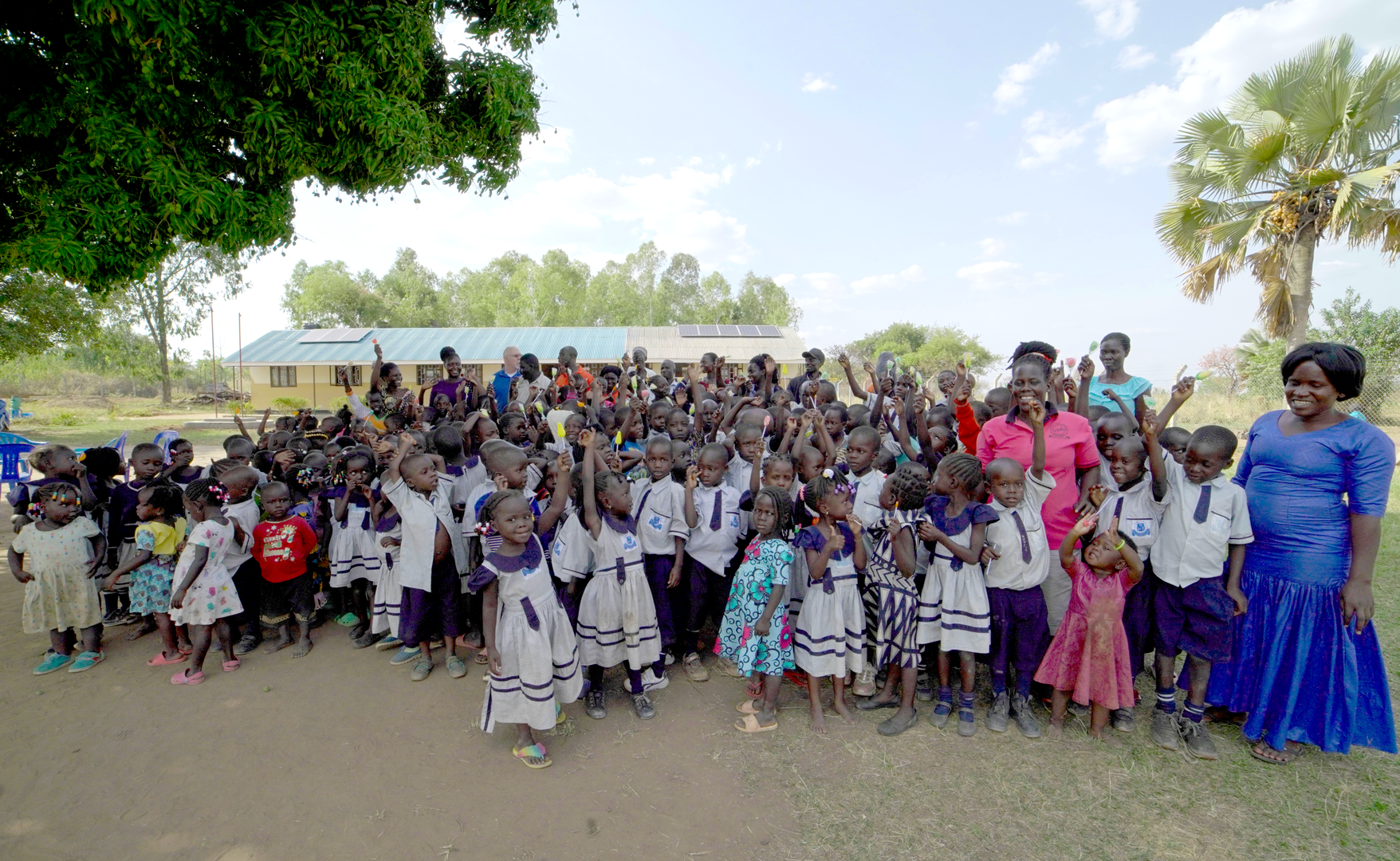 A woman in a blue dress is standing in front of a large group of children.