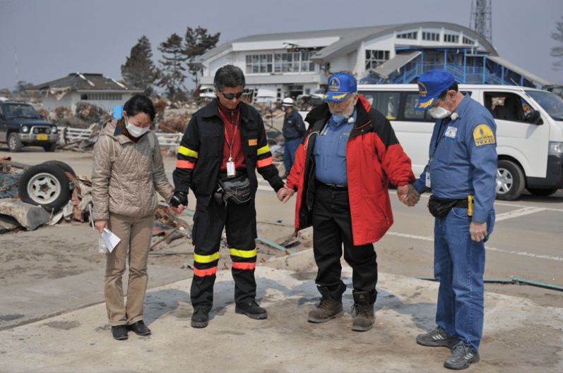 A group of people are standing in a parking lot holding hands.