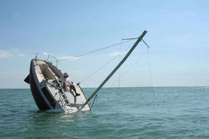 A man sits on the side of a boat in the ocean