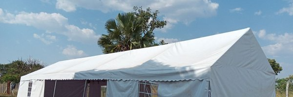 A large white tent is sitting in the middle of a field.