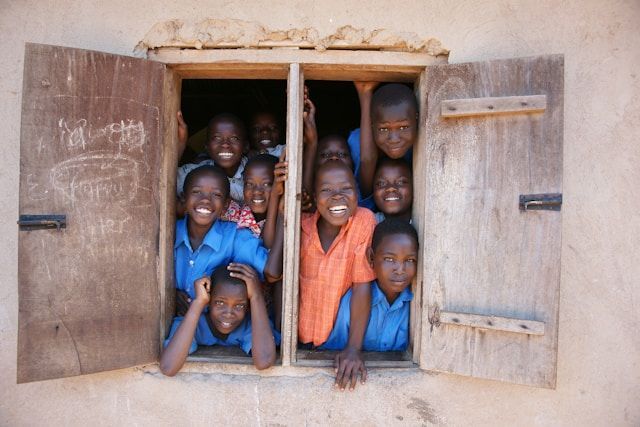 A group of children are looking out of a window and smiling