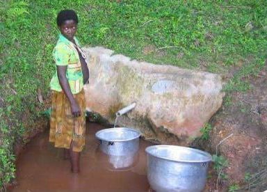 A woman is standing next to two metal bowls of water.