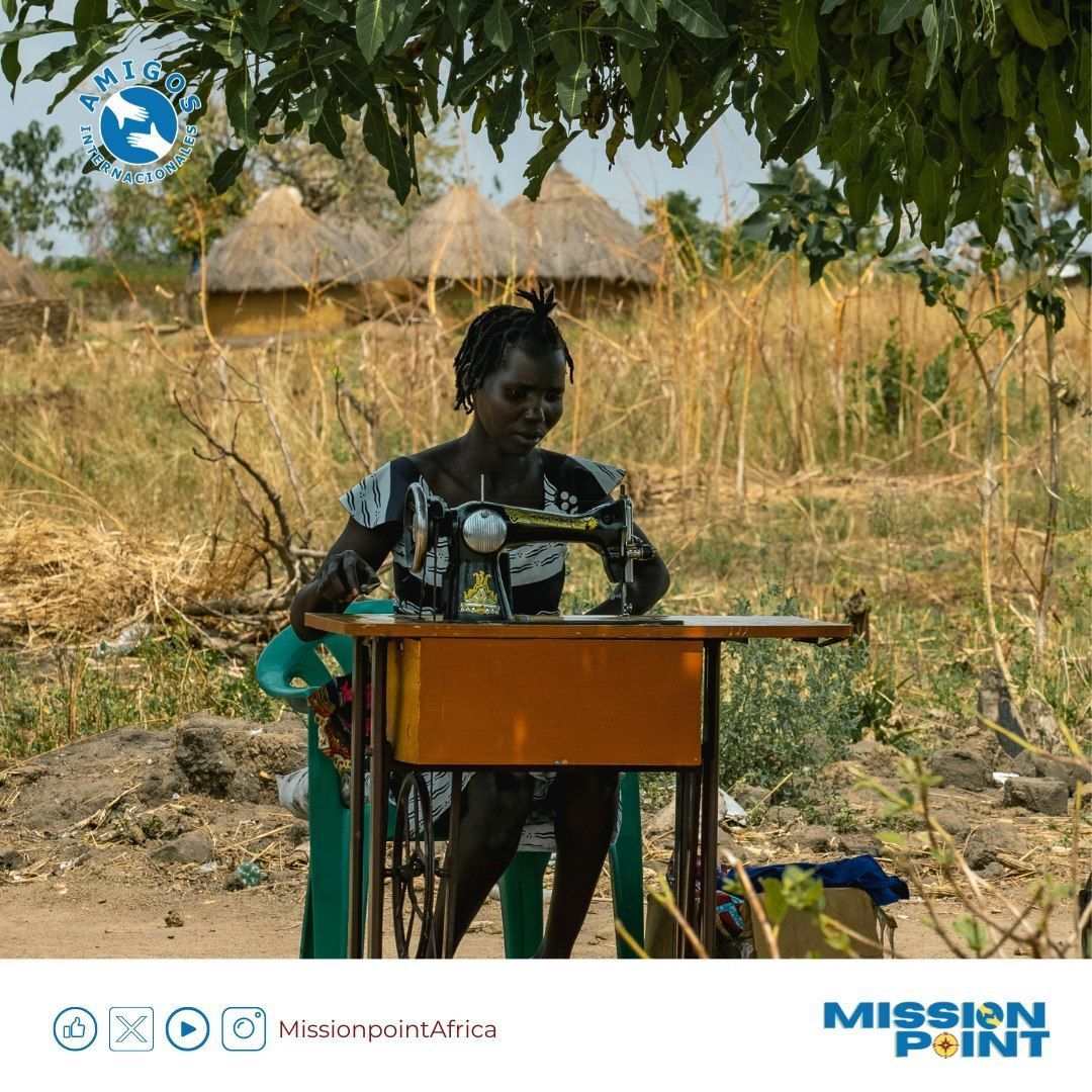 A woman is sitting at a table using a sewing machine sponsored by mission point
