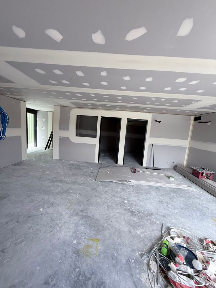 Unfinished garage interior with drywall patches, concrete floor, and open doorway to another room.