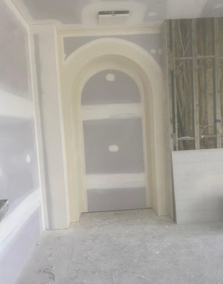 Partially finished room with a cream arched niche and exposed construction materials