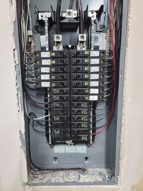 Open electrical breaker panel with exposed wiring and multiple circuit breakers.