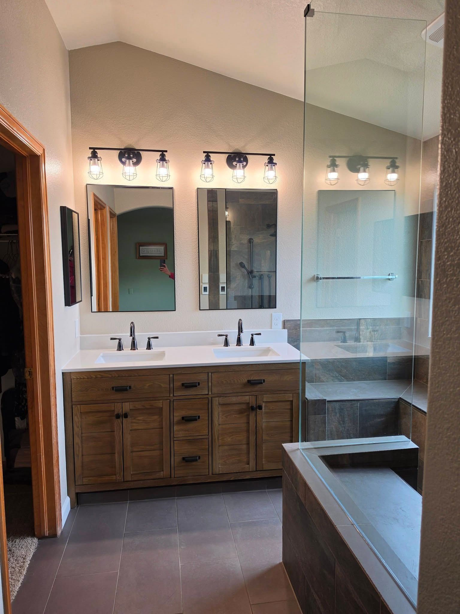 Spacious bathroom with double vanity, large mirror, wood cabinets, and a glass shower beside a bathtub.