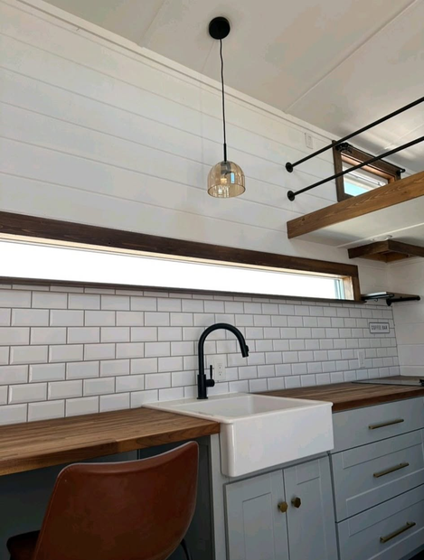 Modern kitchen with white subway tile, wood countertops, black faucet, and hanging pendant light