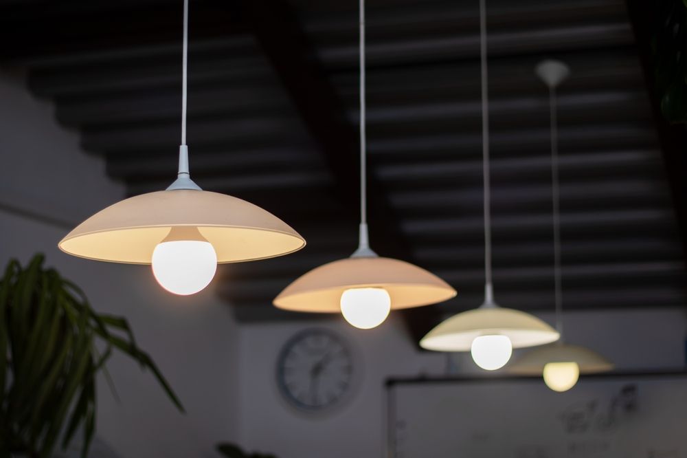 Row of warm pendant lights hanging from a dark ceiling in a modern interior