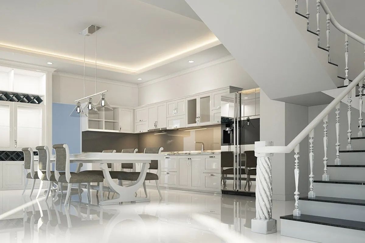Modern white kitchen and dining area with a staircase, featuring glossy floors, pendant lighting, and clean, bright decor.