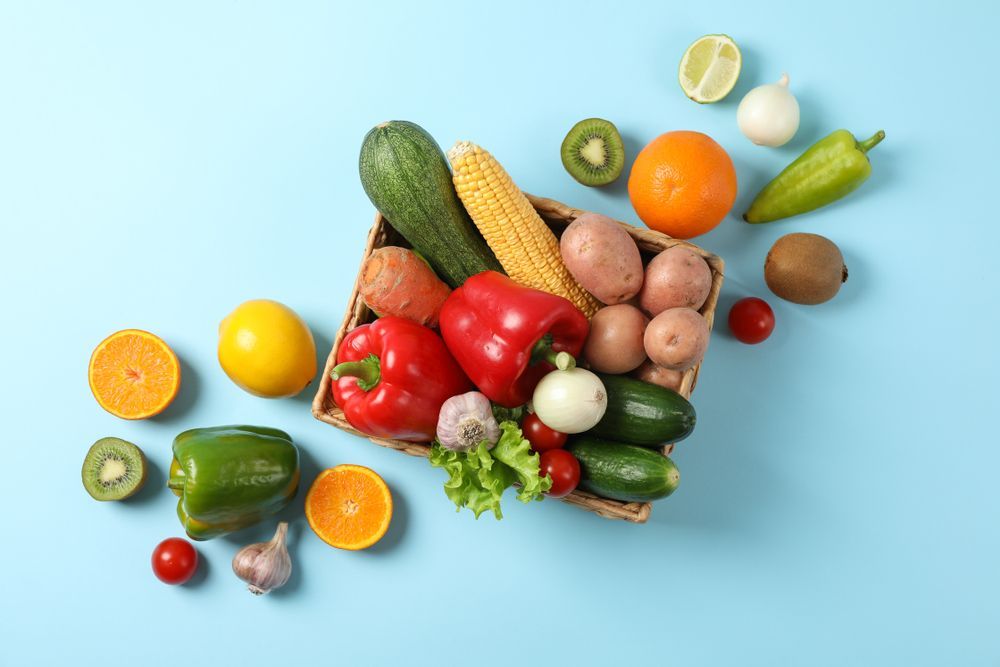A basket filled with fruits and vegetables on a blue background.