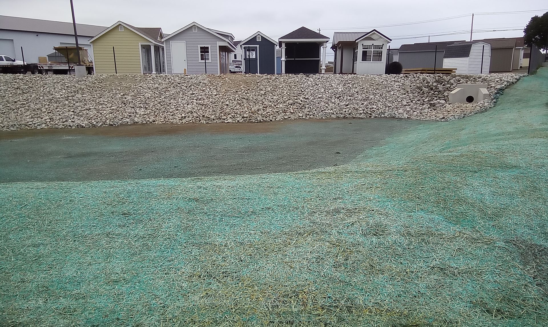 Rock-covered shoreline in front of row houses under an overcast sky