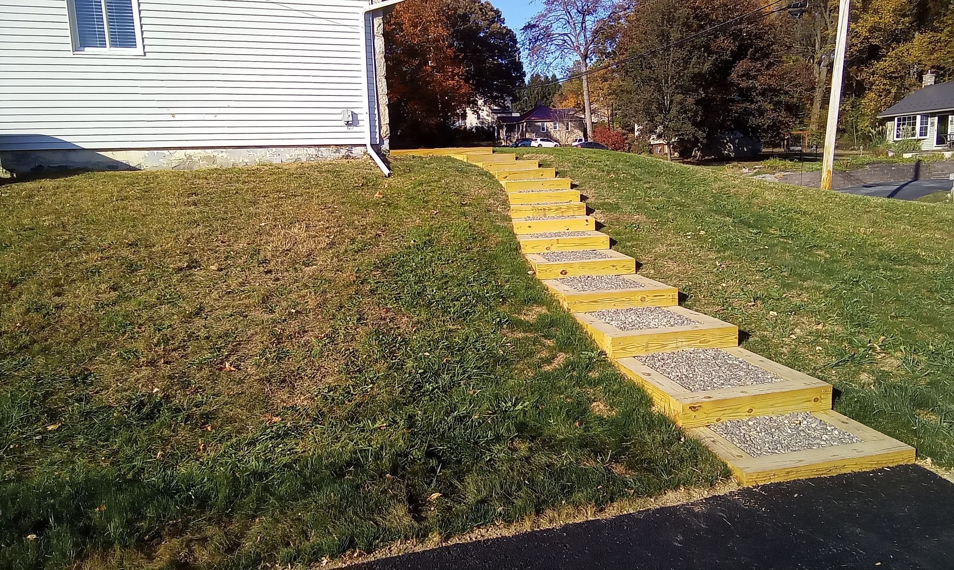 Grassy yard beside a house with yellow-painted stone steps leading up a slope