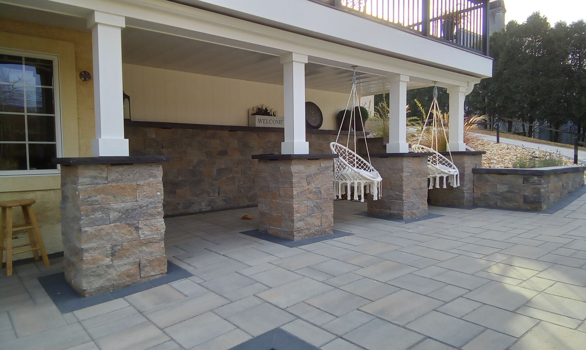 Stone patio with white columns and benches outside a building