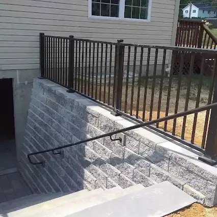 Stone retaining wall with metal railing and stairs leading down.