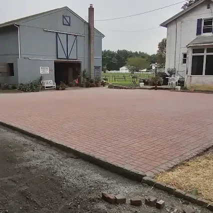 Barn and house, with a brick paved area in between.