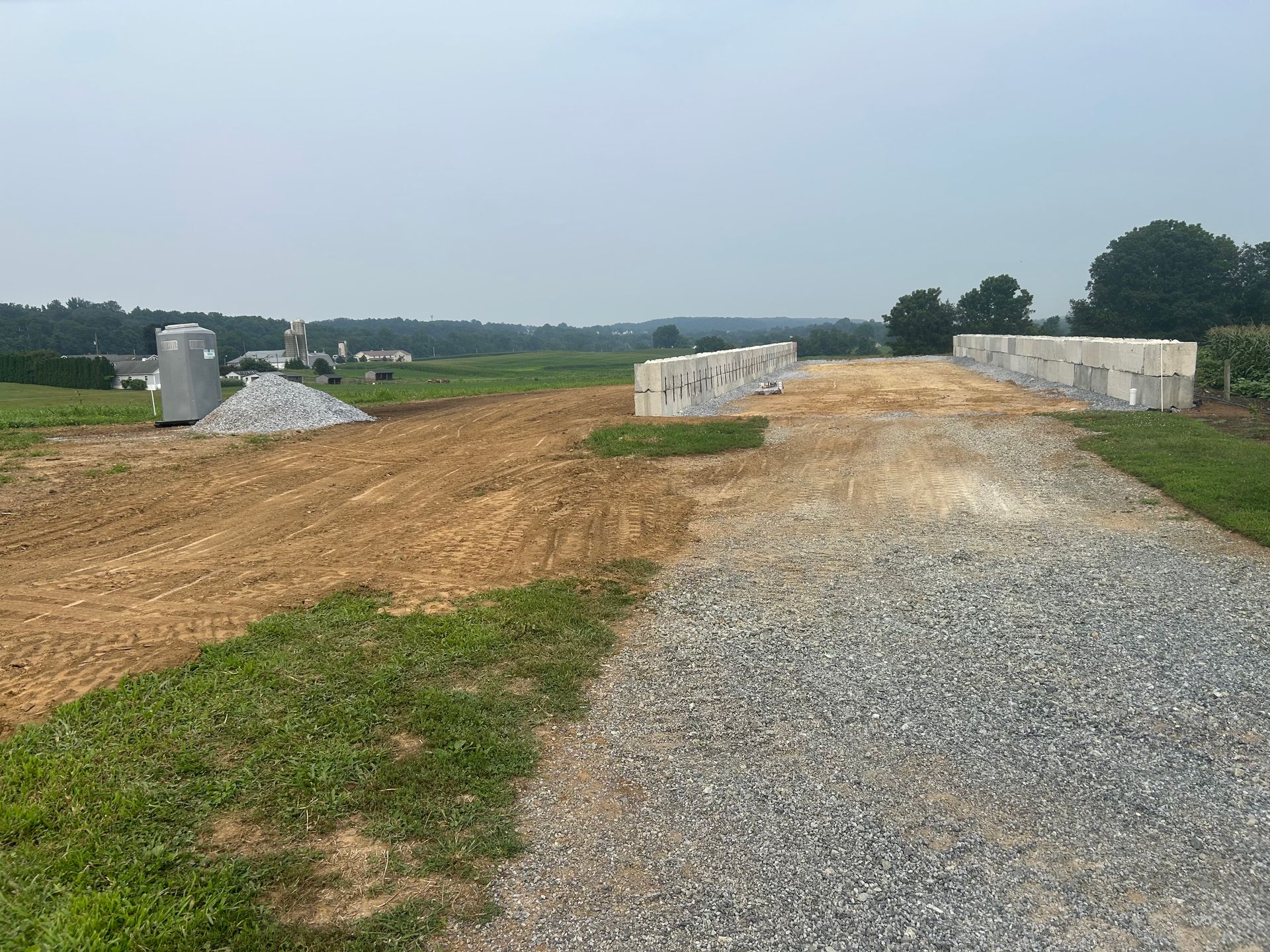Dirt and gravel path construction site with stacked concrete blocks in a field.