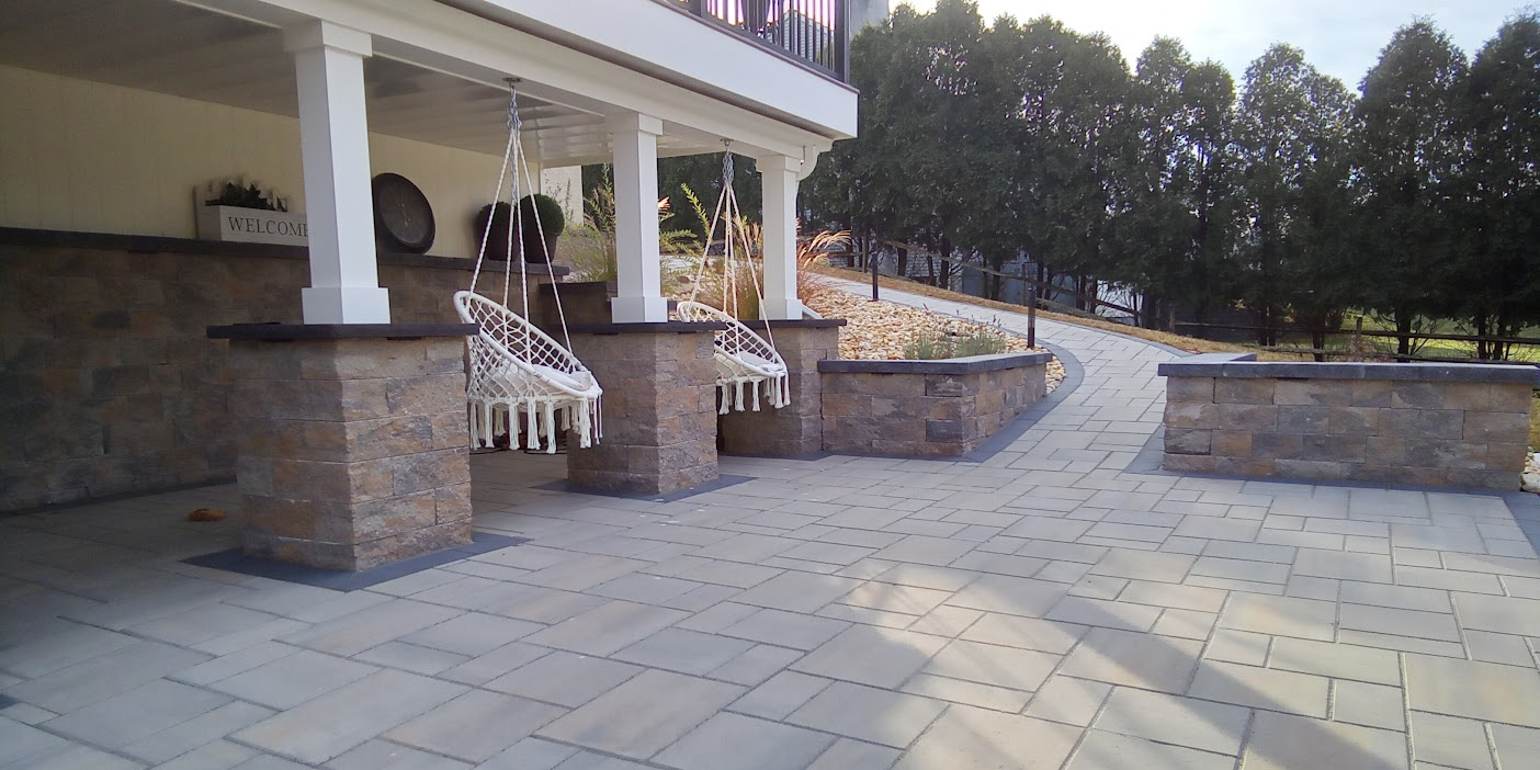 Front porch with hanging chairs, stone columns and walkway.