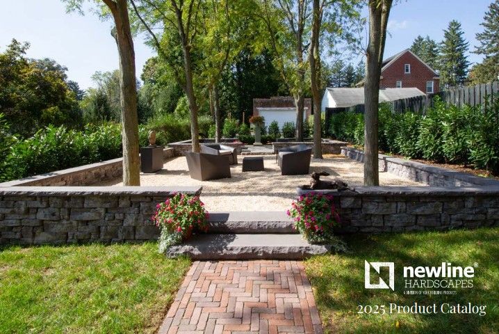 Stone-walled outdoor seating area with gravel, trees, and brick pathway.